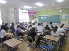 テレビの点いた教室で勉強をする子供たちの写真
