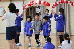 2つの紅白のアーチを3人で手をつないでくぐる子供たちの写真