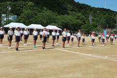 校庭で児童たちが等間隔で並んで立っている写真