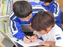 低学年の子に問題の解き方を教える高学年の子