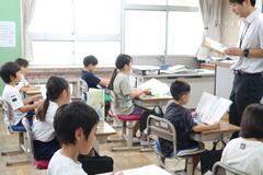 教科書を見ている子供たちと、教科書を見ながら話す大人の写真