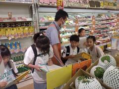 スーパーの店内で定員に取材をする子供たちの写真