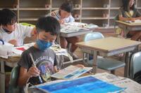 子供が教室で絵の具を使い絵を描いている写真