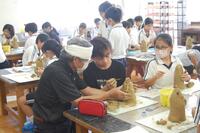 教室で先生から埴輪づくりのレクチャーを受けながら作成を進める生徒たちの写真