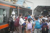 教師に誘導されて電車に乗り込んでいる生徒たちの写真