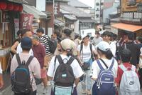 両側に店のある通りを歩く生徒たちの写真
