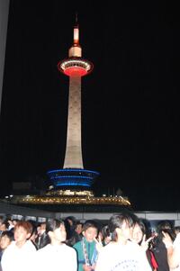 夜の京都タワーの前で写真を撮っている生徒たちの写真