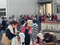建物の前に首にタオルをかけた人々が集まっている写真