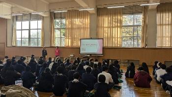 体育館で座っている御津あおば高校の1年生に対して、北村さんがスクリーンを用いてがんの説明をしている写真