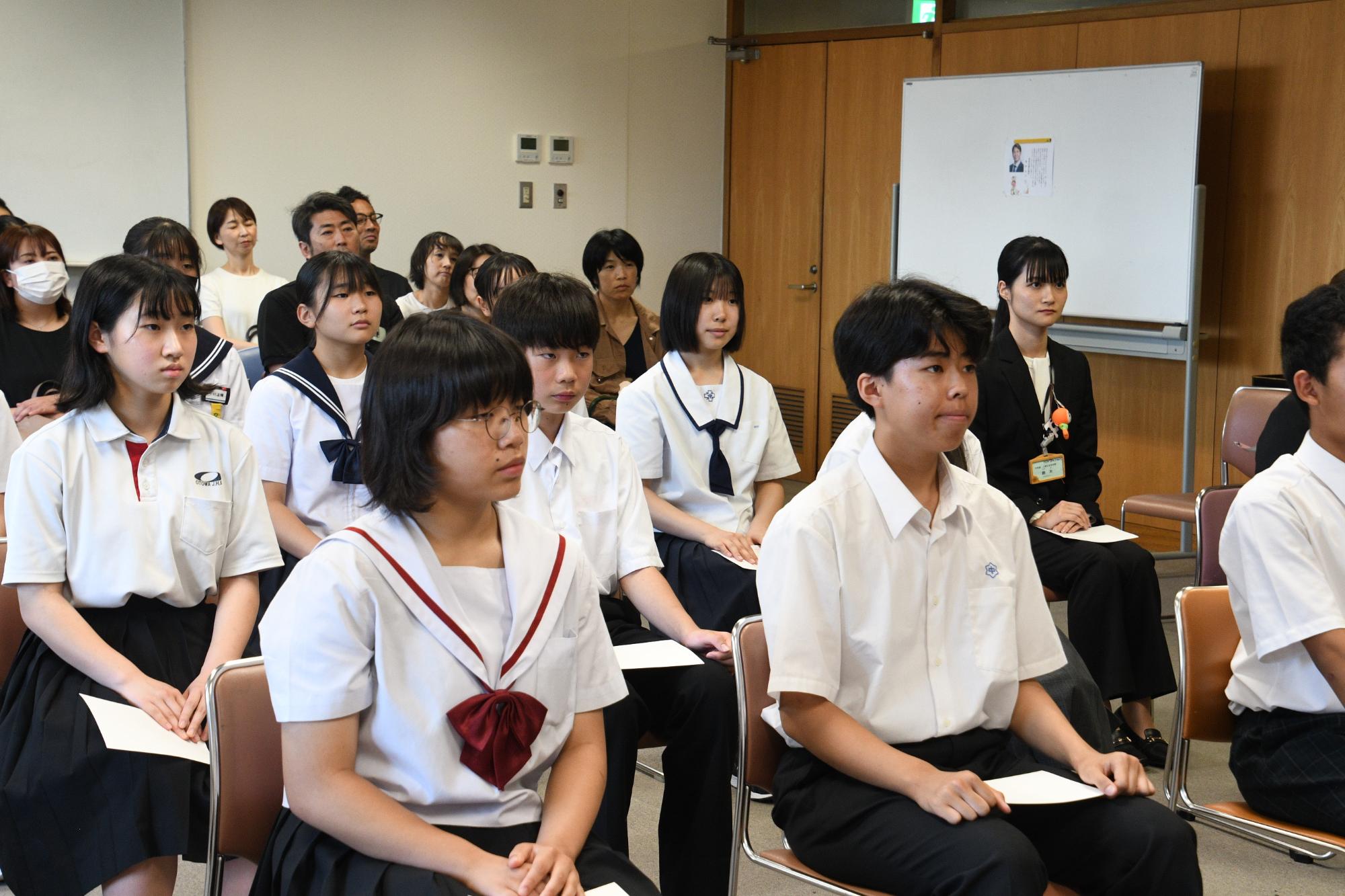 制服やスーツを着ている人たちが座っている写真