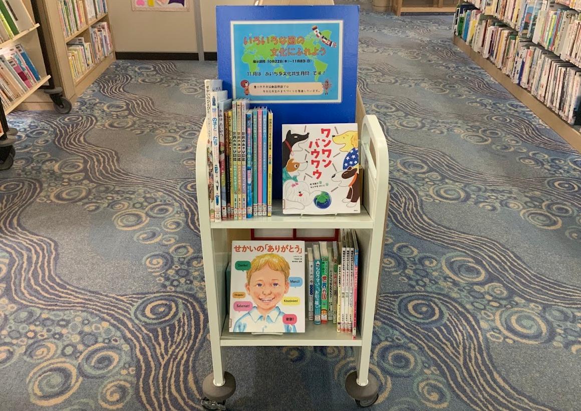 2段の本棚の上に青色の「いろいろな国の文化にふれよう」と書かれた看板が置いてある写真