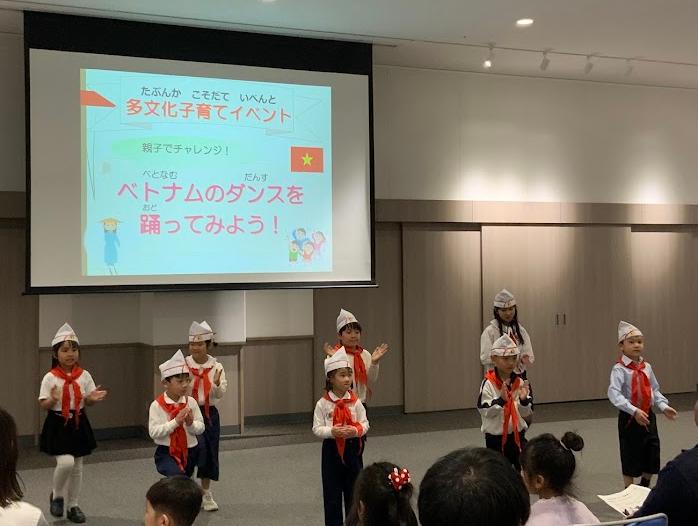 赤い隊員スカーフを首に巻いたベトナム人の子供たちがスクリーンの前でダンスをしている写真