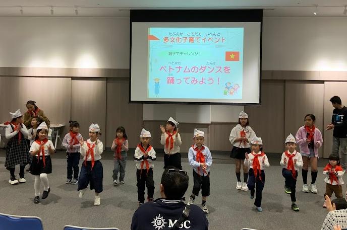 赤い隊員スカーフを首に巻いた子供たちがスクリーンの前でダンスをしている写真