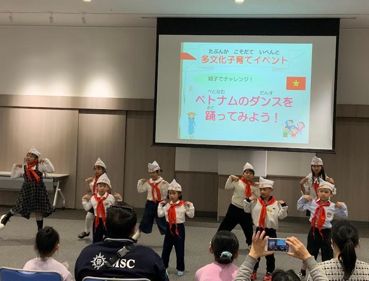 赤い隊員スカーフを首に巻いたベトナム人の子供たちがスクリーンの前でダンスをしている写真