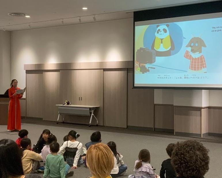 アオザイを着た女性がベトナム語で絵本を読んでいる写真