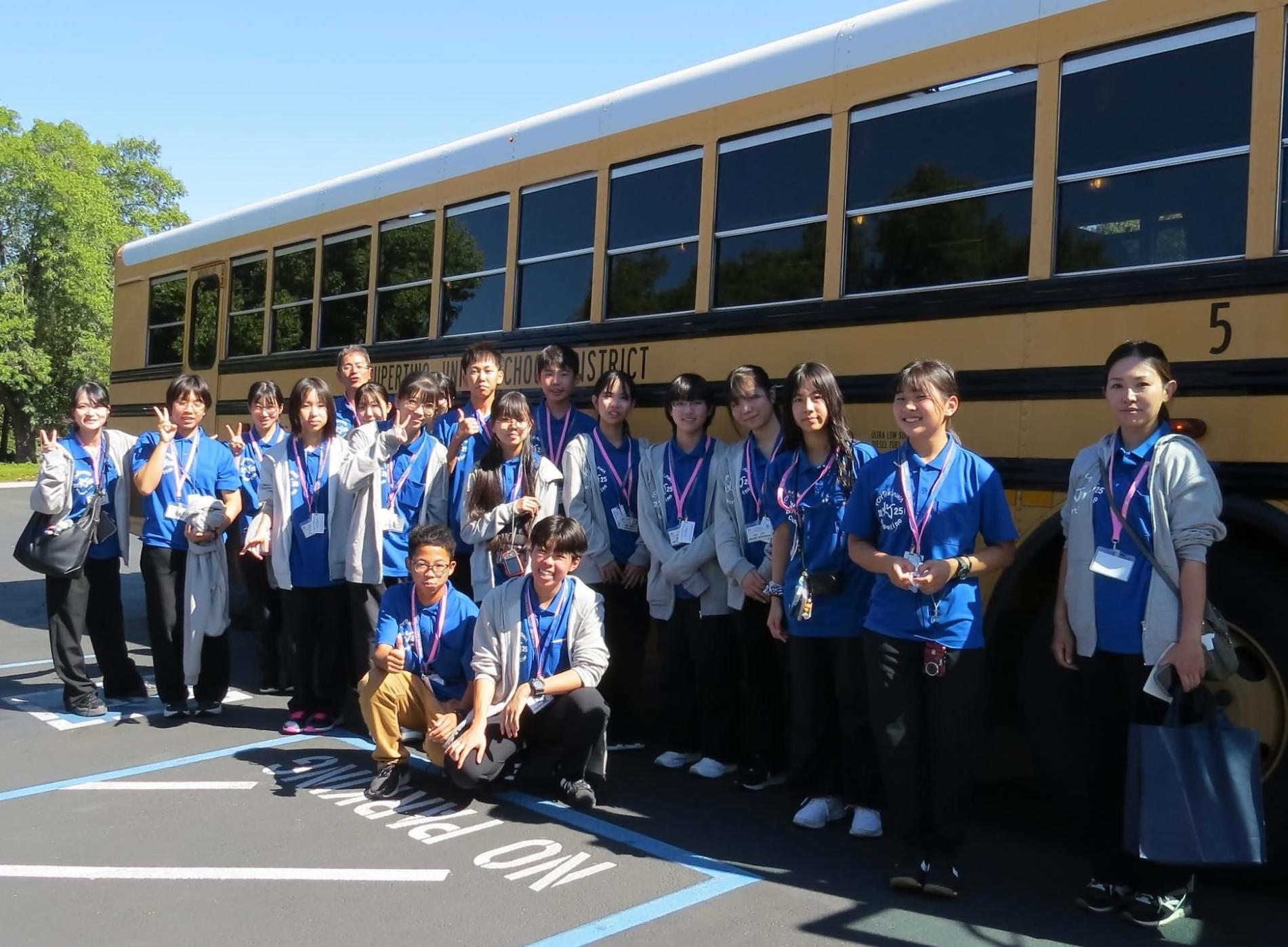 黄色いバスの前で学生たちが立っている写真