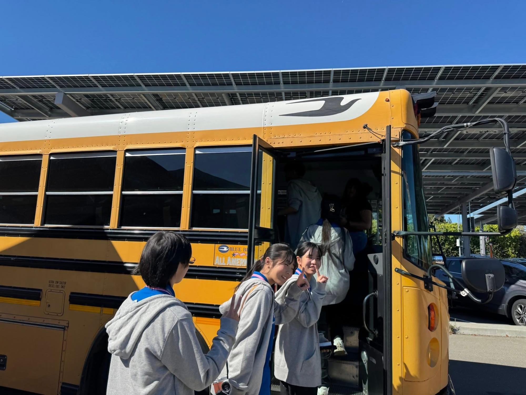 黄色いバスのに学生が並んで乗ろうとしている写真