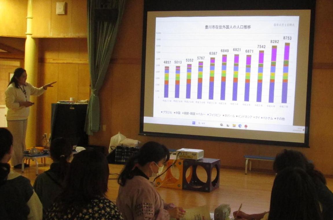 女性が、座っている保育士の前で説明している写真