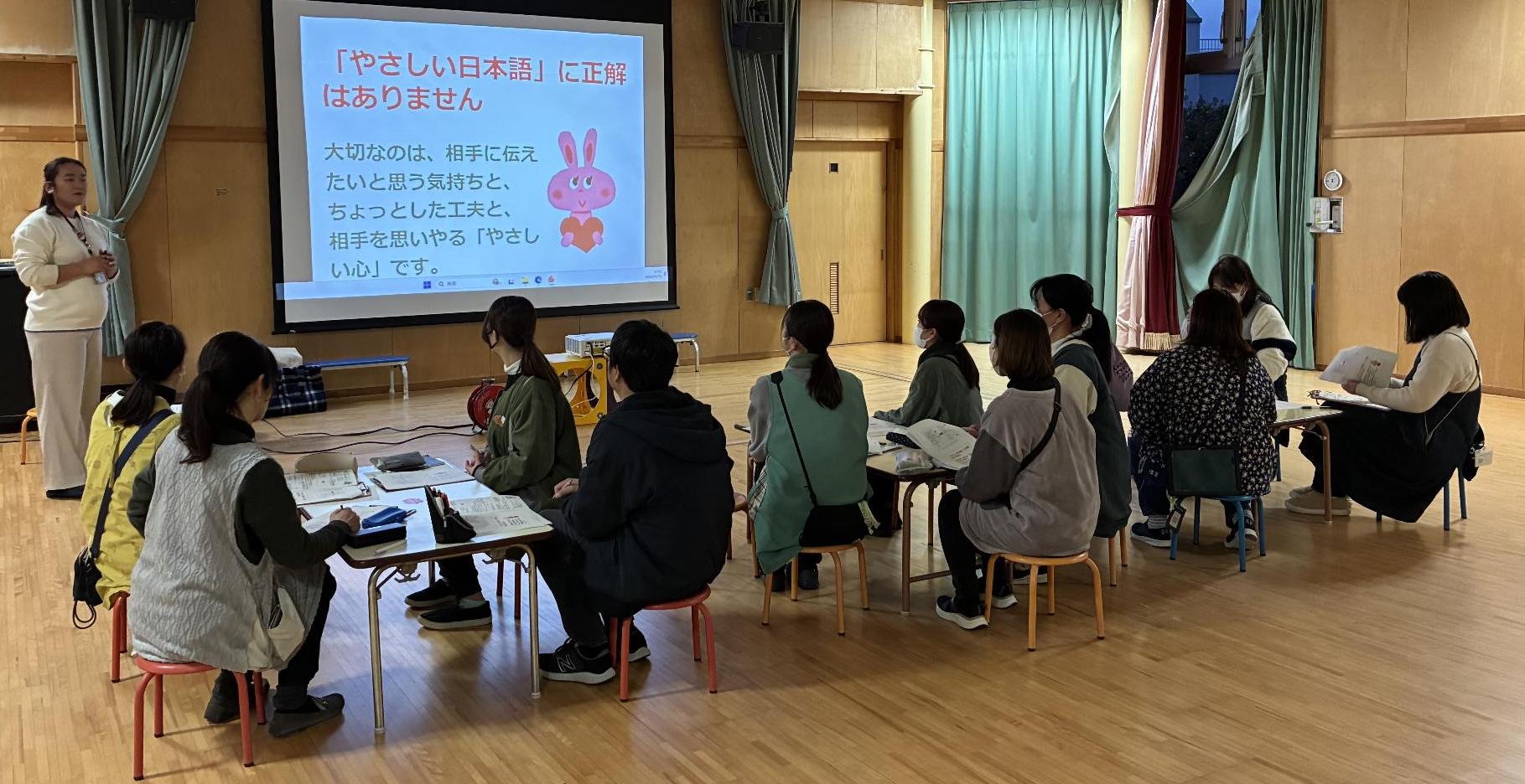 女性が、座っている保育士の前で説明している写真