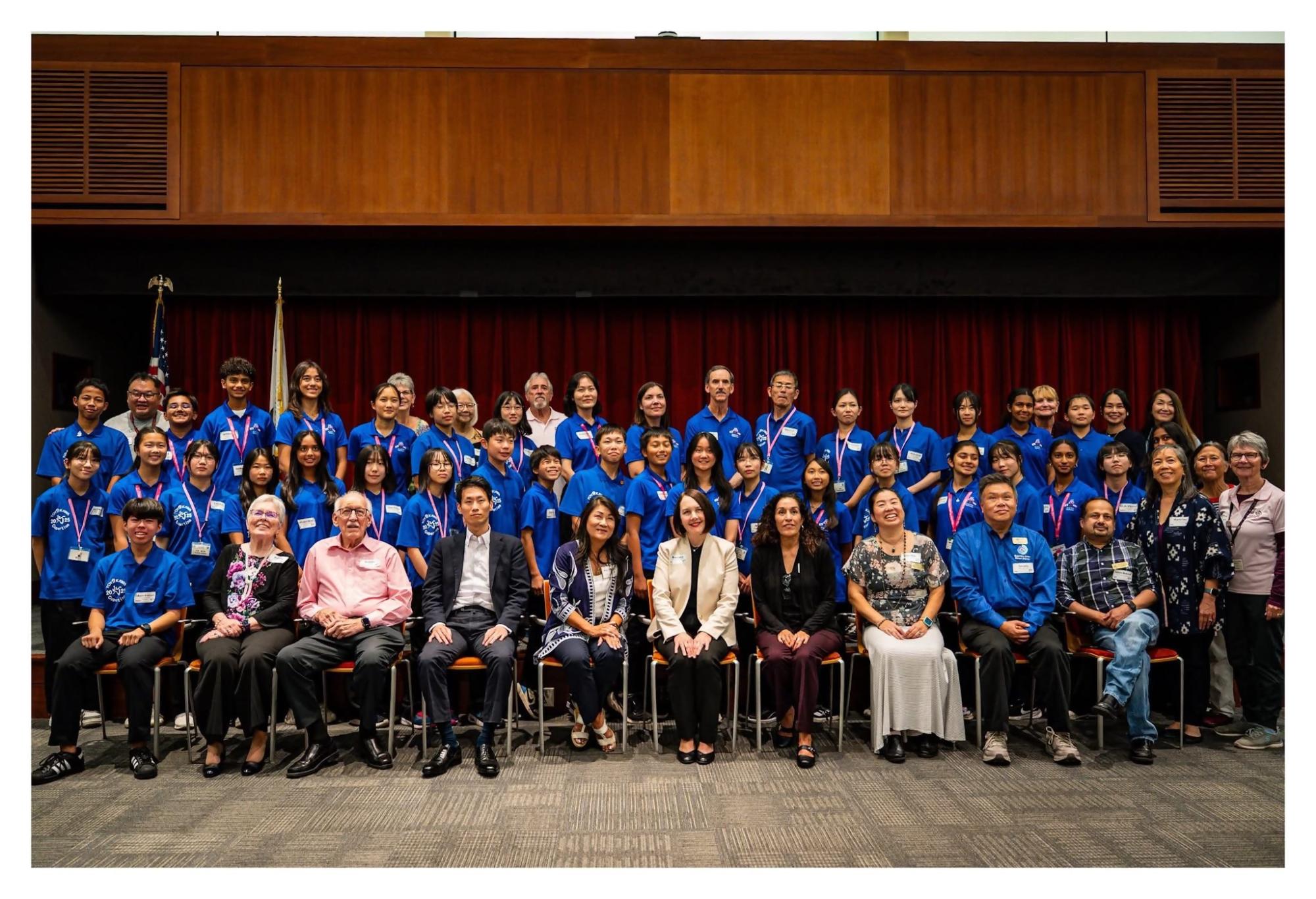 たくさんの青い服を着た人たちとスーツを着た人達の集合写真