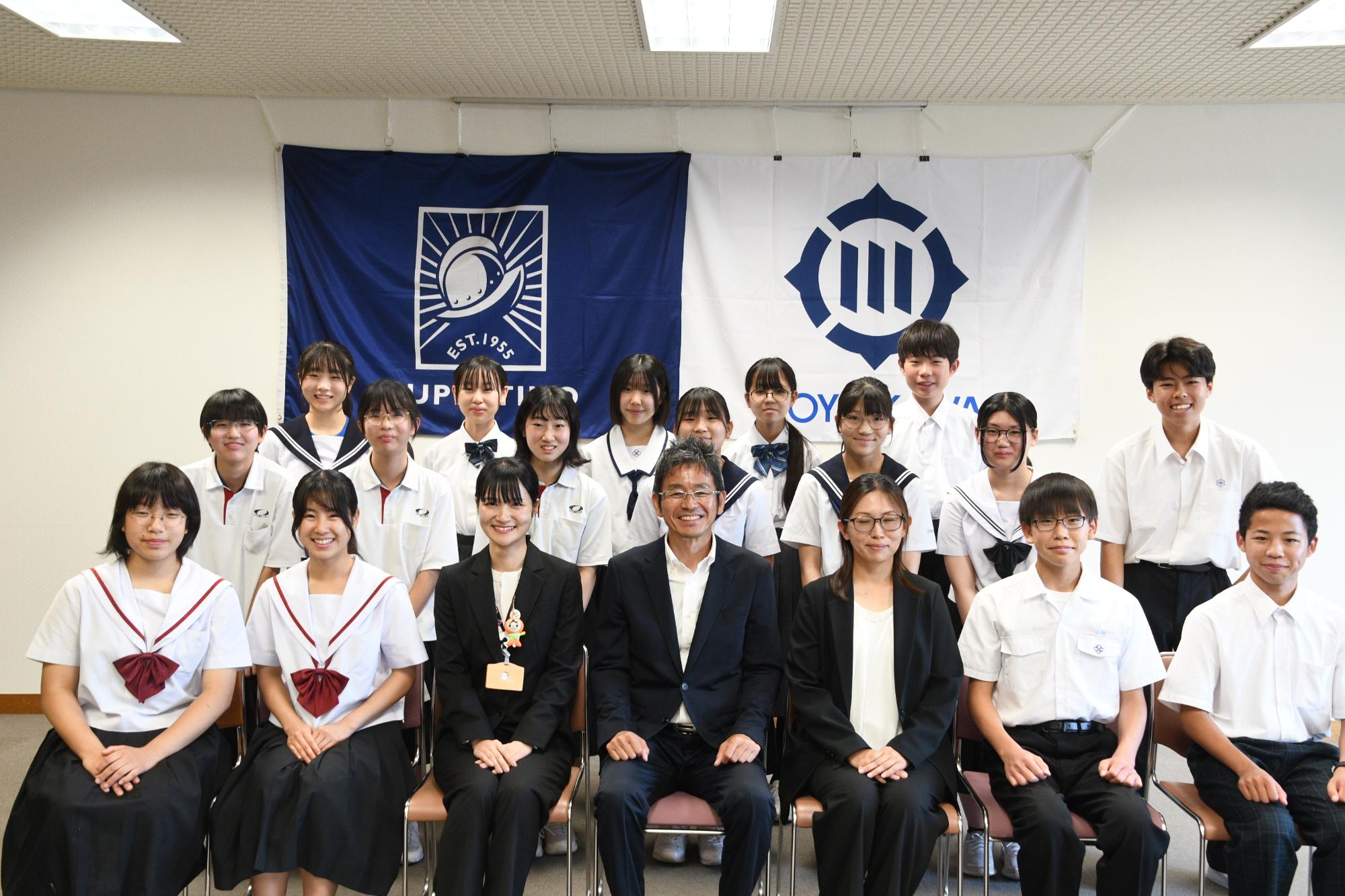 スーツや制服を着ている人たちが集まっている写真
