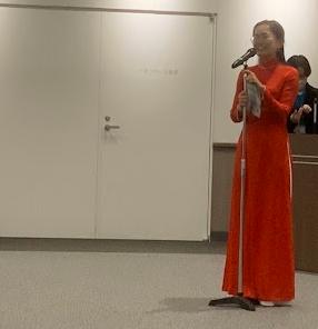 アオザイを着た女性が立ってベトナム語で自己紹介をしている写真