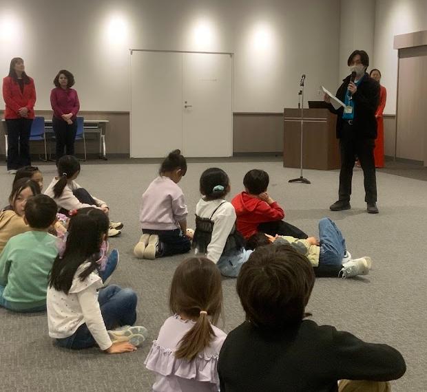 青色のポロシャツを着た男性がマイクを持ってしゃべっている写真