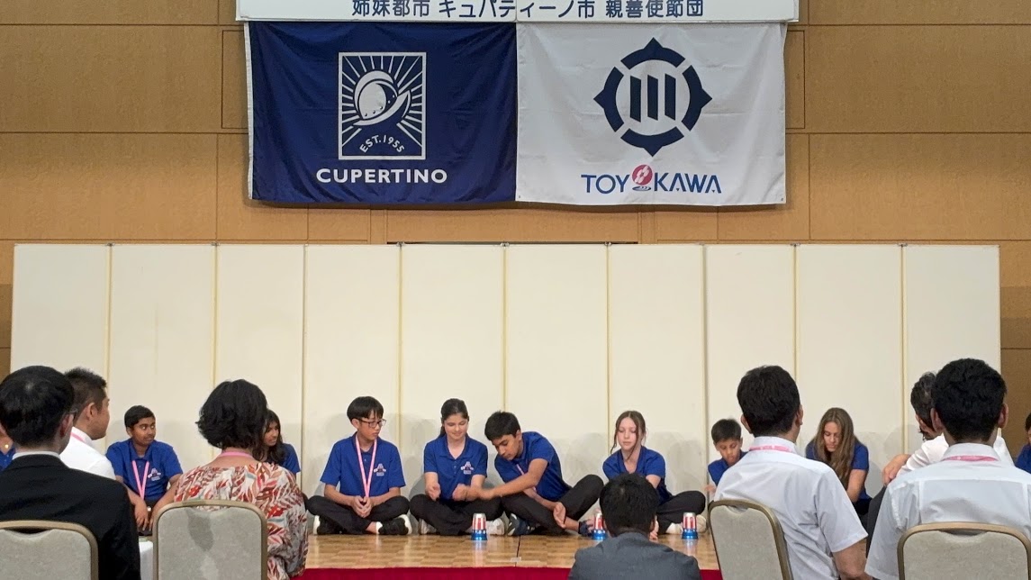 青い服を着た人達がカップを使ってパフォーマンスをしている様子