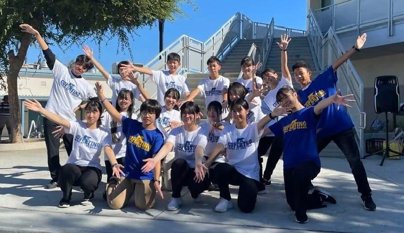 白色と青色のTシャツを着た中学生が手を広げてポーズをしている写真