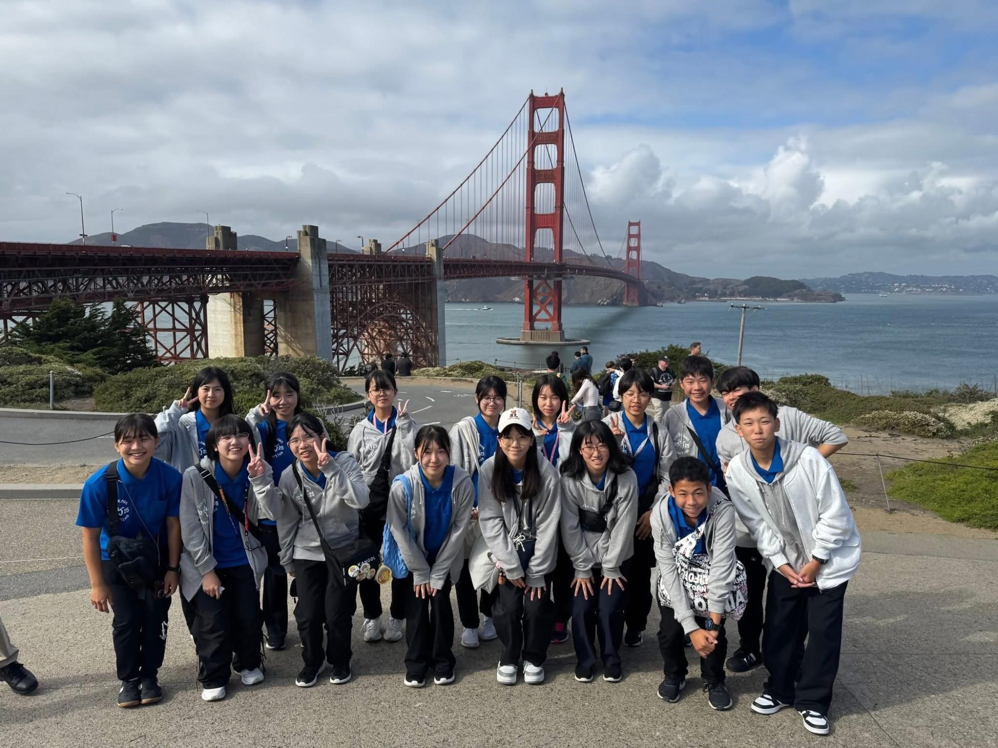 灰色のパーカーを着た人たちが橋の前で集まっている写真