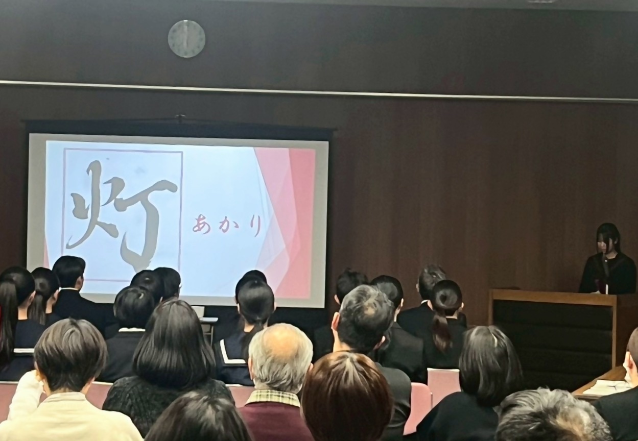 制服を着た女子生徒がスクリーンに映像を映しながら発表している写真