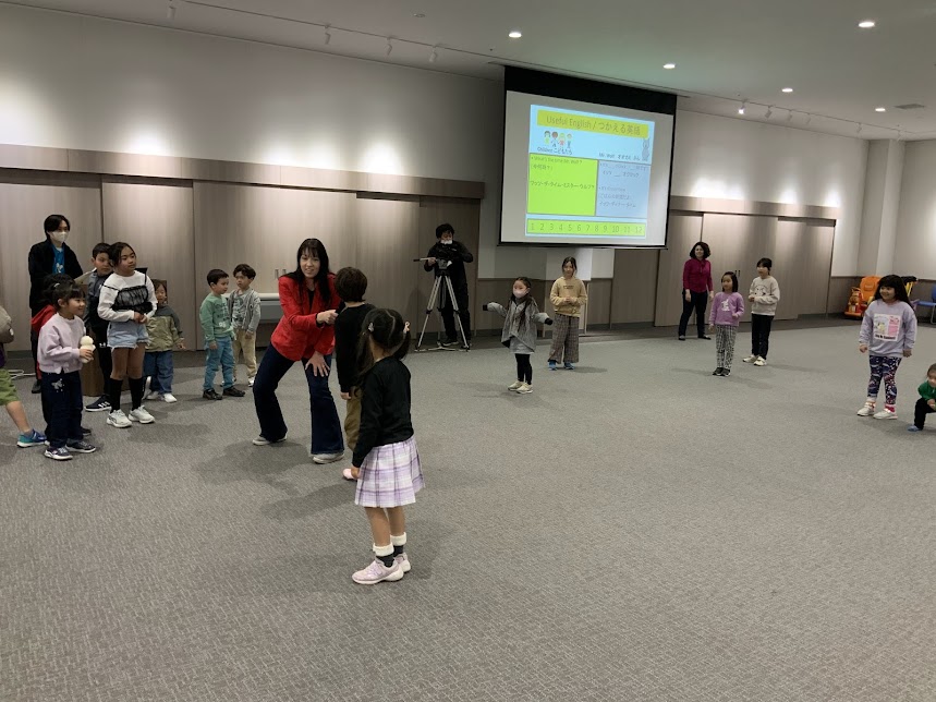 赤い服を着た女性が男の子にマイクを向けている写真