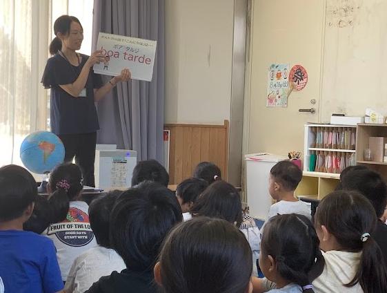 教室で大人が資料を子どもたちに見せている写真