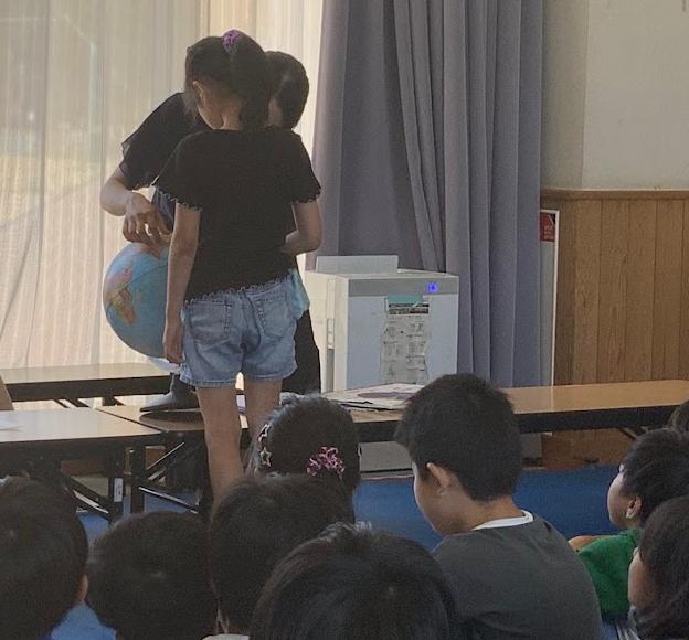 教室で大人が地球儀を子どもたちに見せている写真