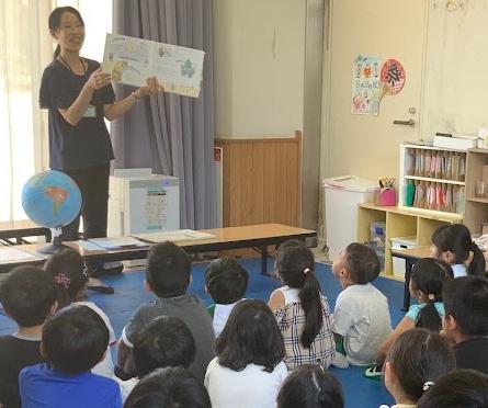 教室で大人が絵本を子どもたちに見せている写真