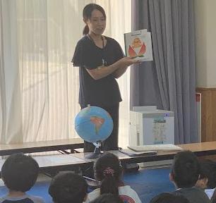 教室で大人が絵本を子どもたちに見せている写真