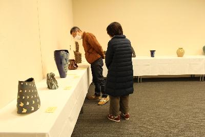 展覧会の様子（陶芸の部の作品とそれを見ている人）