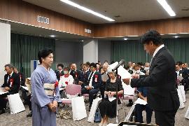 男性と女性が向かいあい、片方の男性が賞状を手渡している写真