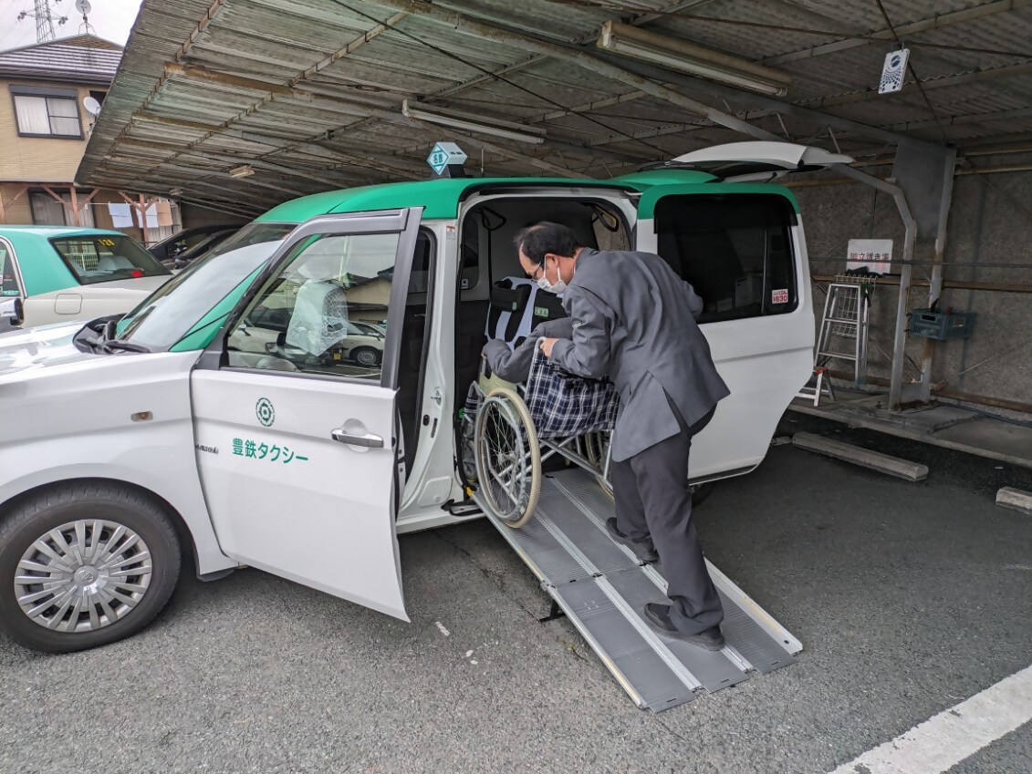 スロープの準備されたユニバーサルデザインタクシーに乗り込む画像