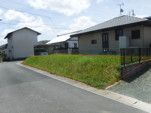 住宅の隣にある雑草地が赤い線で囲われている写真