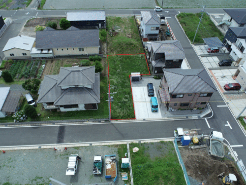 住宅と住宅の間にある雑草地の下半分が赤い線で囲われている写真