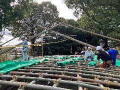 丸太と竹を組んで部隊の観客席を作る小屋掛け作業の写真