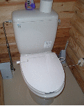 貯水タンクの上にトイレットペーパーと芳香剤が置かれた白い洋式トイレの写真