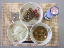 テーブルクロスに並べられたごはん・牛乳・のっぺい汁・ぶた肉のしょうが炒め・ミニトマト・ココア糖の写真