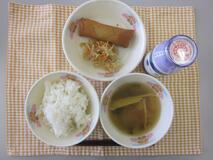 テーブルクロスに並べられたごはん・牛乳・中華スープ・はるまき・もやしのあま酢あえの写真