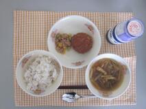 テーブルクロスに並べられた麦ごはん・牛乳・沢煮わん・和風コロッケ・ツナそぼろ丼の写真