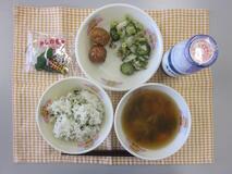 テーブルクロスに並べられたわかめごはん・牛乳・すまし汁・ごぼう入りつくね・赤しそあえ・かしわもちの写真