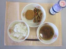テーブルクロスに並べられたごはん・牛乳・いなか汁・キャベツ入りメンチカツ・糸切りこんぶの煮付けの写真