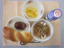 テーブルクロスに並べられたツイストパン・牛乳・やさいスープ・ハンバーグのワインソースかけ・フルーツゼリーミックスの写真