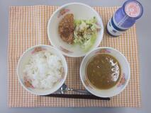 テーブルクロスに並べられたごはん・牛乳・米粉のカレースープ・チキンハムカツ・ボイルキャベツの写真